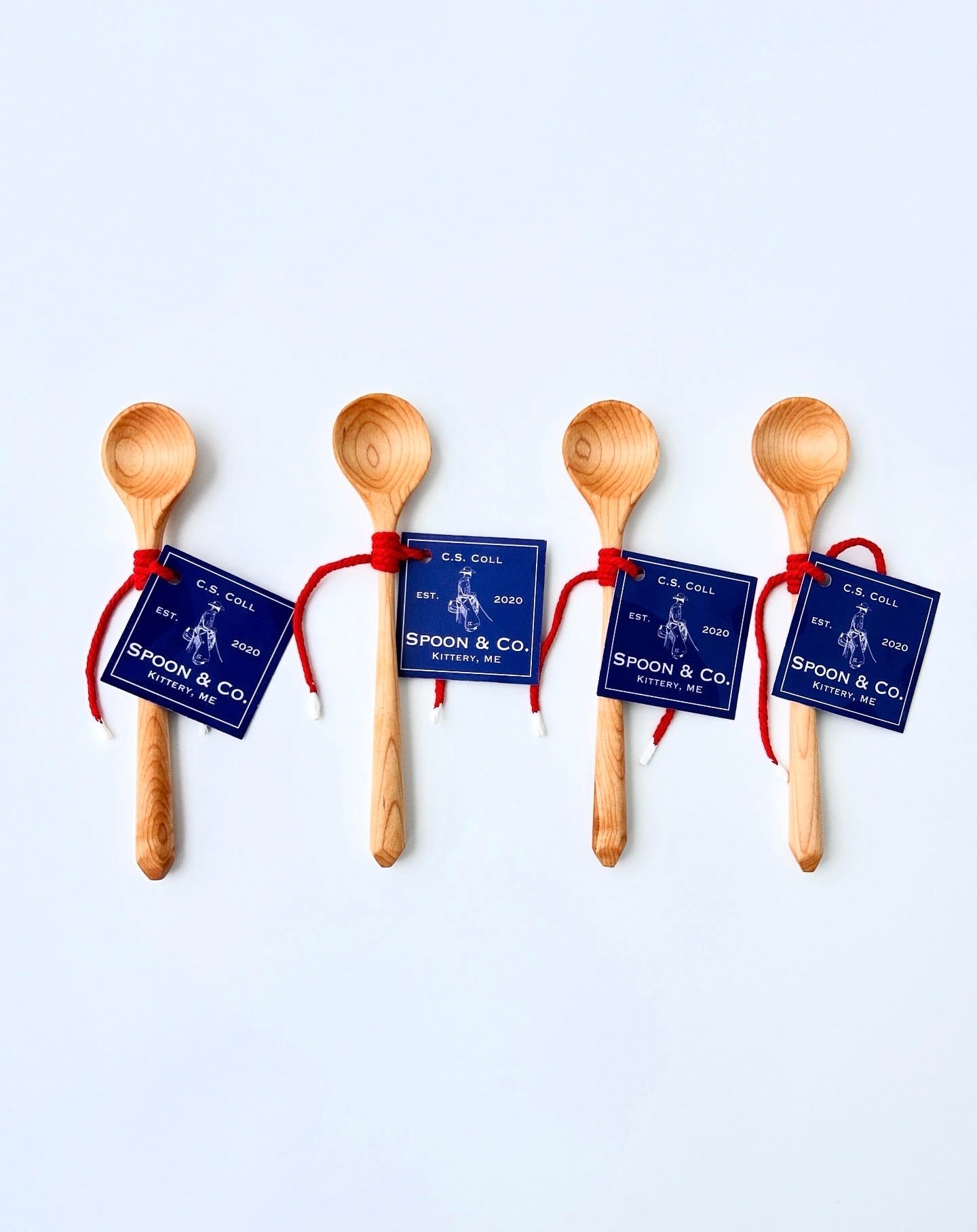Four wooden spoons with blue labels on a light gray background